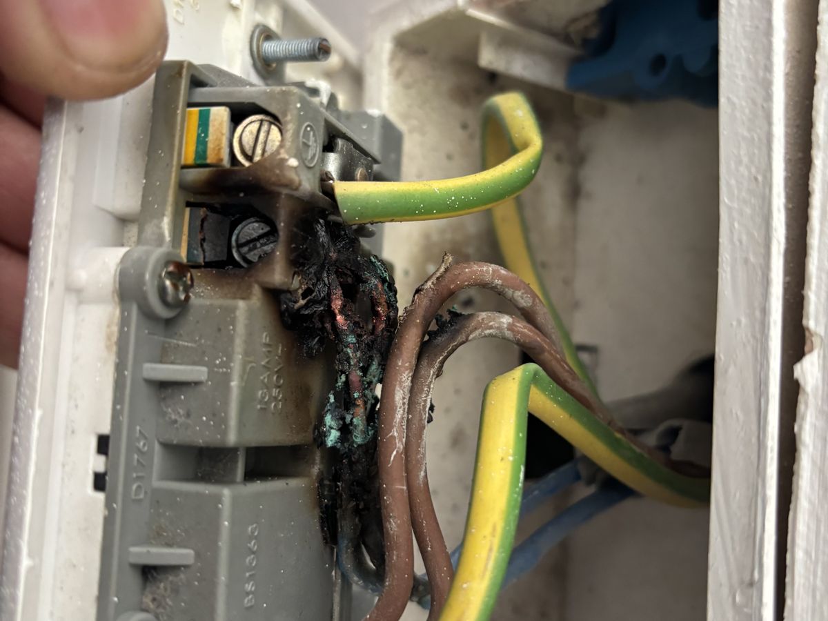 Burnt live cable behind a socket in a London home